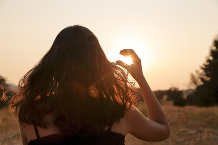 The woman capturing the sunset with fingers frame in Turkey. And her hair is broken.の写真素材