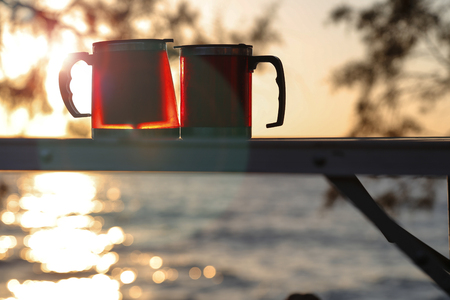 Couple thermos cup with sunset. Picnic time for lovers.の写真素材