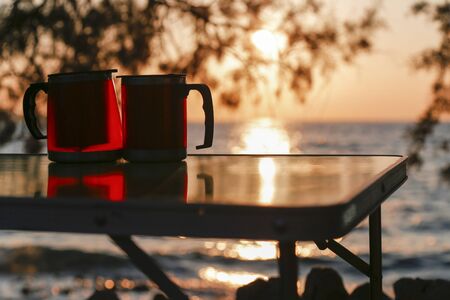 Couple thermos cup with sunset. Picnic time for lovers.の写真素材