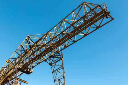 Vintage working gantry crane rusty yellow, bottom view, close-up against a blue spring skyの写真素材