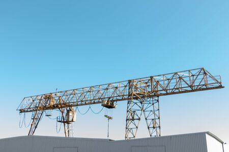 Vintage working gantry crane rusty yellow, bottom view, close-up against a blue spring skyの写真素材