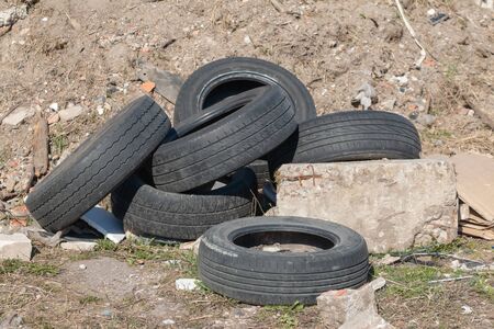 Old used tires lie near a pile of construction debrisの写真素材