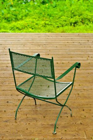 An empty chair sits on a wooden deck with acornsの写真素材