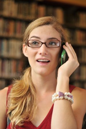 Teenage girl in library on phoneの写真素材