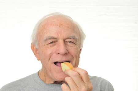 A happy man eats a slice of apple.の写真素材