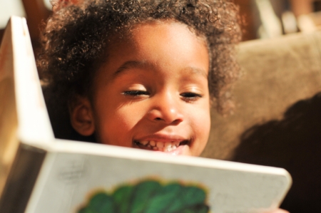 Curly hair mixed race boy reads a bookの写真素材
