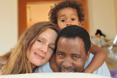 Family of mixed race play together on a bedの写真素材