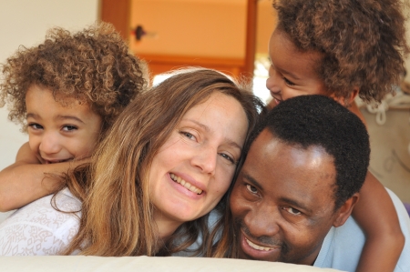 Family of mixed race play together on a bedの写真素材