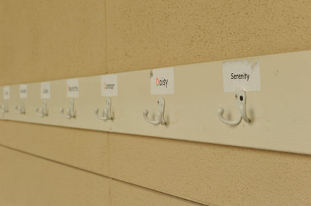 A wall with names for each hook to hang backbacks for school 