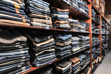 Rows of denim jeans on shelves in a retail storeの写真素材
