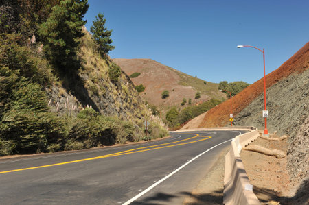 Hill with different color minerals next to a road curving by