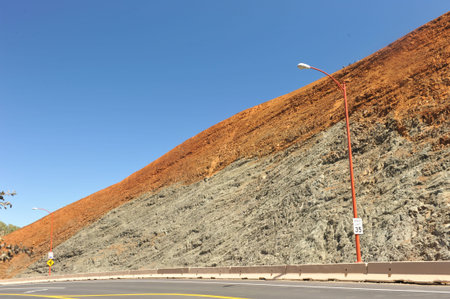 Hill with different color minerals next to a road curving byの写真素材