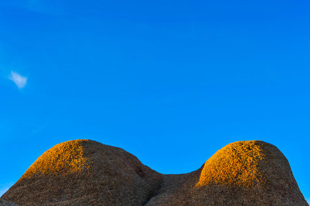 Blue sky with a mound of rocks that looks like the chest of a woman