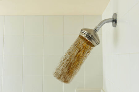 Dirt flowing from a shower head because of droughtの写真素材