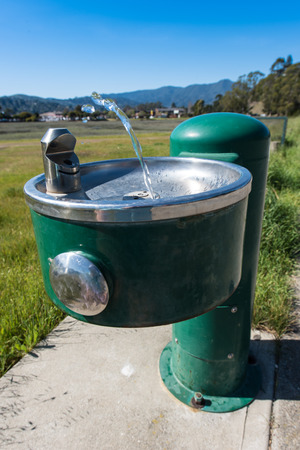 A stream of water flows from a drinking fountain but runs out mid flowの写真素材