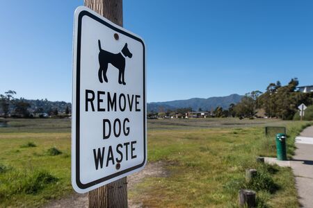 Sign with Remove Dog Waste next to a green park areaの写真素材