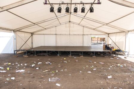 Garbage and litter on floor of tent with stage and lightsの写真素材