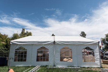 White canopy with four windows and a white picket fence in grass fieldの写真素材