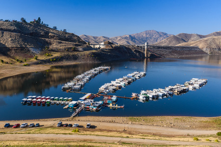 Low lake level with a marina with many boats and some cars.のeditorial素材