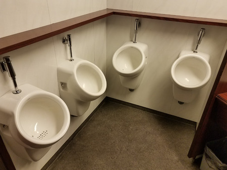 Four urinals spaced close together in a bathroomの写真素材