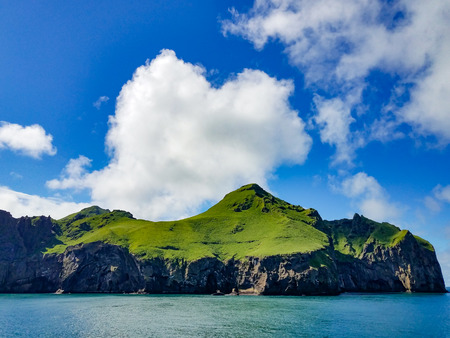 Green mountains under cloudy sky by the oceanの写真素材