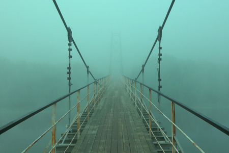 Suspension bridge over the river,during fog.の写真素材