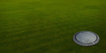 Sewer hatch on the green meadow.の写真素材