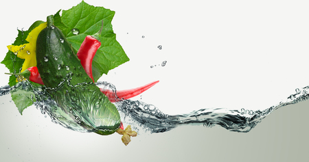 Fresh cucumber and chili pepper in a spray of water.の写真素材