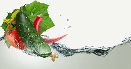 Cucumber, tomato and pepper in a spray of water.の写真素材