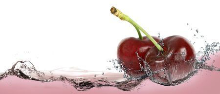 Ripe cherries in a spray of cherry drinkの写真素材