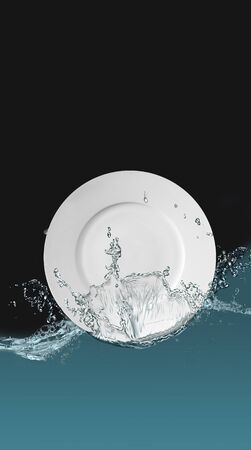 Clean plate in spray of water on a black background.の写真素材
