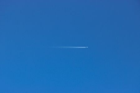 Passenger plane flying in a cloudless blue sky.の写真素材