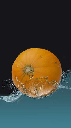 Ripe melon in a spray of water, on a black background.の写真素材