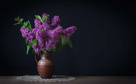 Dark lilac flowers in a ceramic pot on the table.の写真素材