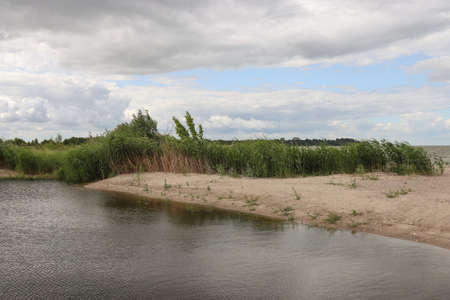 The landscape by the lake against the backdrop of the cloudy sky.の写真素材