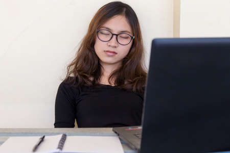 Young woman tired of working, doing homework, with notebook and laptopの写真素材