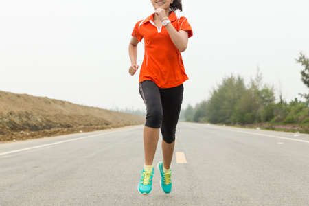 young woman running on roadの写真素材