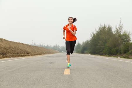 young woman running on roadの写真素材