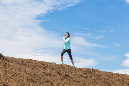 young woman running on trail with blue sky backgroundの写真素材