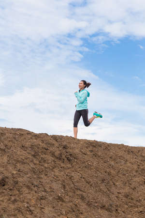 young woman running on trail with blue sky backgroundの写真素材