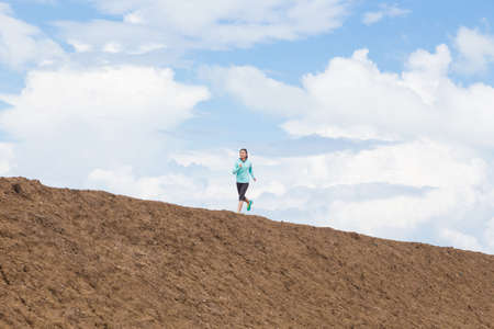 young woman running on trail with blue sky backgroundの写真素材