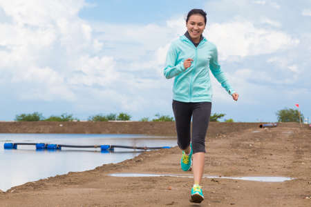 young woman running on trail with blue sky backgroundの写真素材