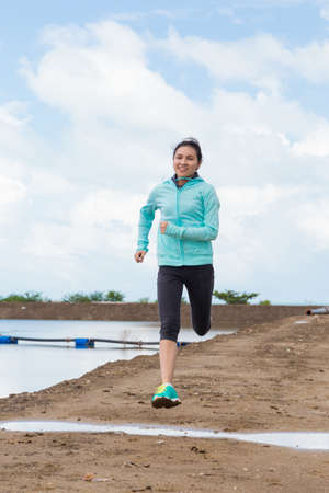 young woman running on trail with blue sky backgroundの写真素材
