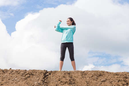 young woman stretching before Fitness and Exercise on mountain trail with blue sky backgroundの写真素材