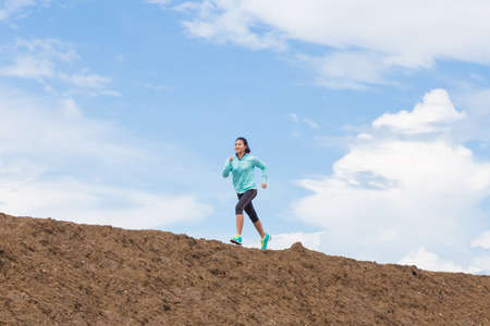 young woman running on trail with blue sky backgroundの写真素材