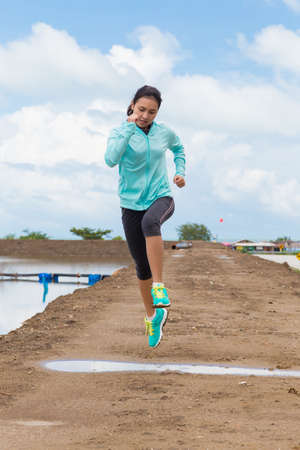 young woman running on trail with blue sky backgroundの写真素材