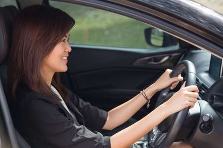 Asian woman driving happy about her new car or drivers licenseの写真素材