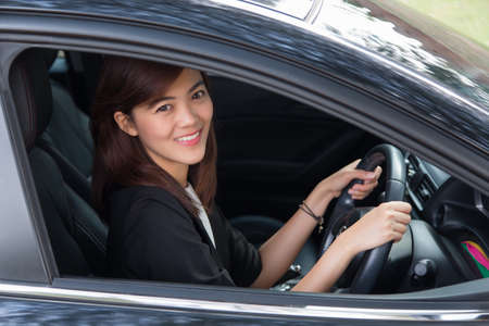 Asian woman driving happy about her new car or drivers licenseの写真素材