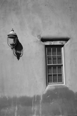 Adobe Building with Window and Light Fixture in black and whiteの写真素材