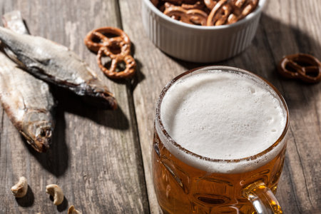 Beer with dried fish and snacks on wooden table